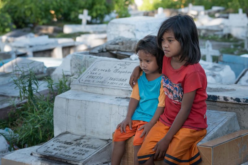 Zwei Kinder sitzen auf Grabstein